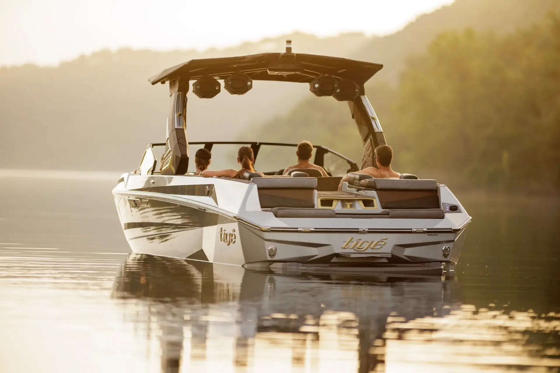 Friends aboard a Tigé ULTRE 25ZX on a glassy lake at golden hour